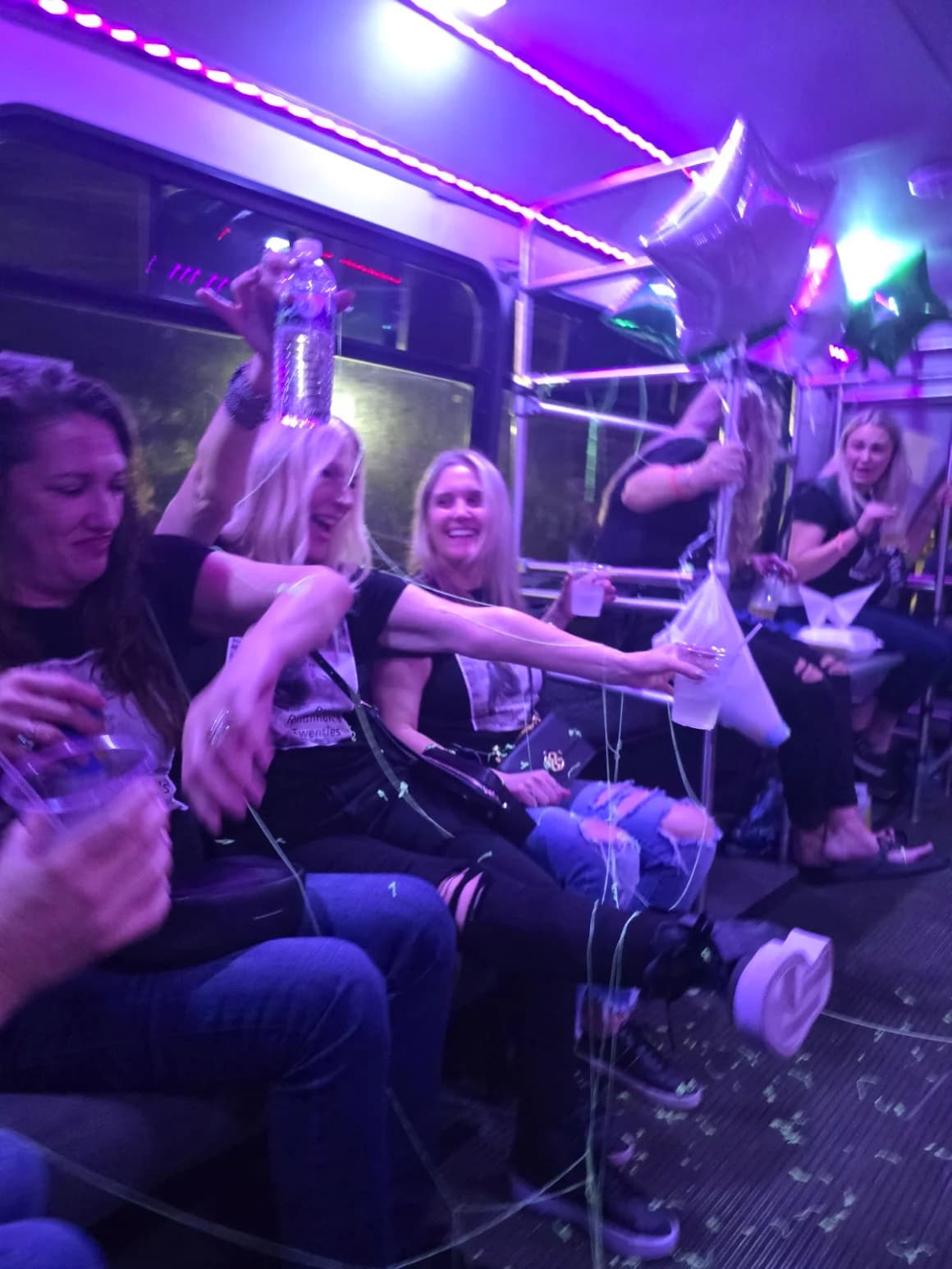 Riders celebrating with balloons and confetti aboard the Frog Hop at night