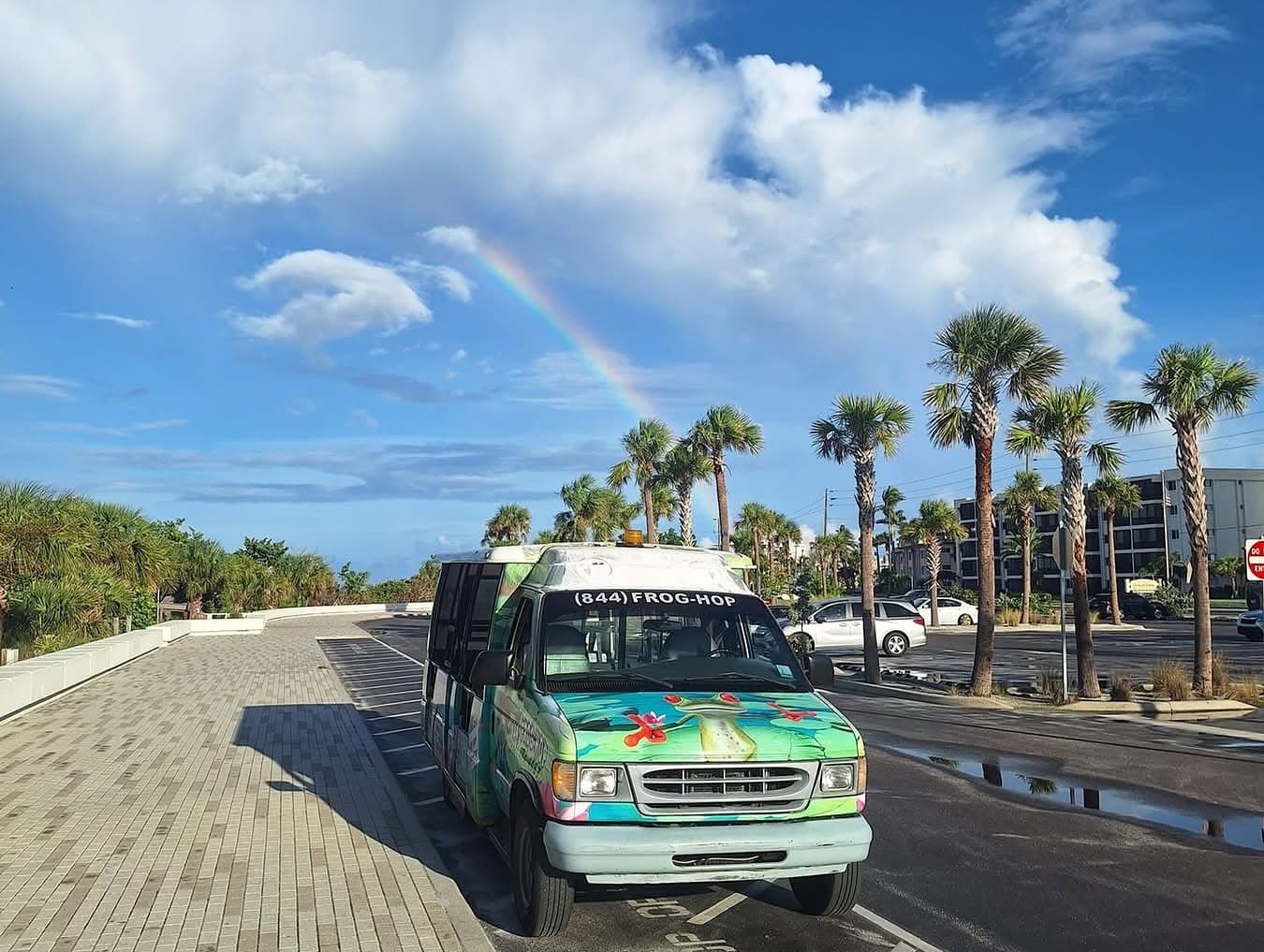 A Frog Hop van parked at Siesta Key beach under a rainbow